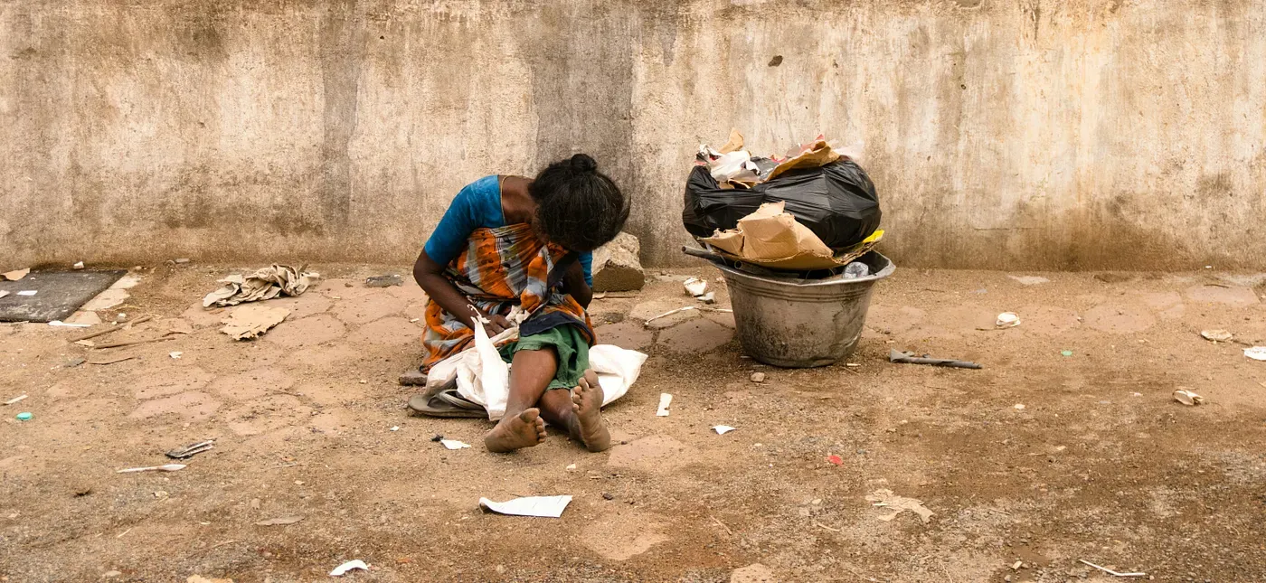 A person sorting materials beside a bucket of discarded paper