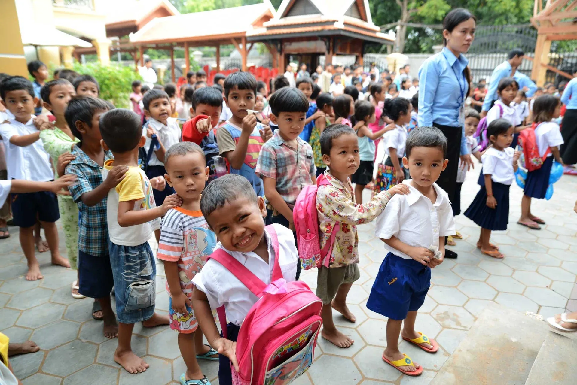 Children in school uniforms smiling together outside a classroom