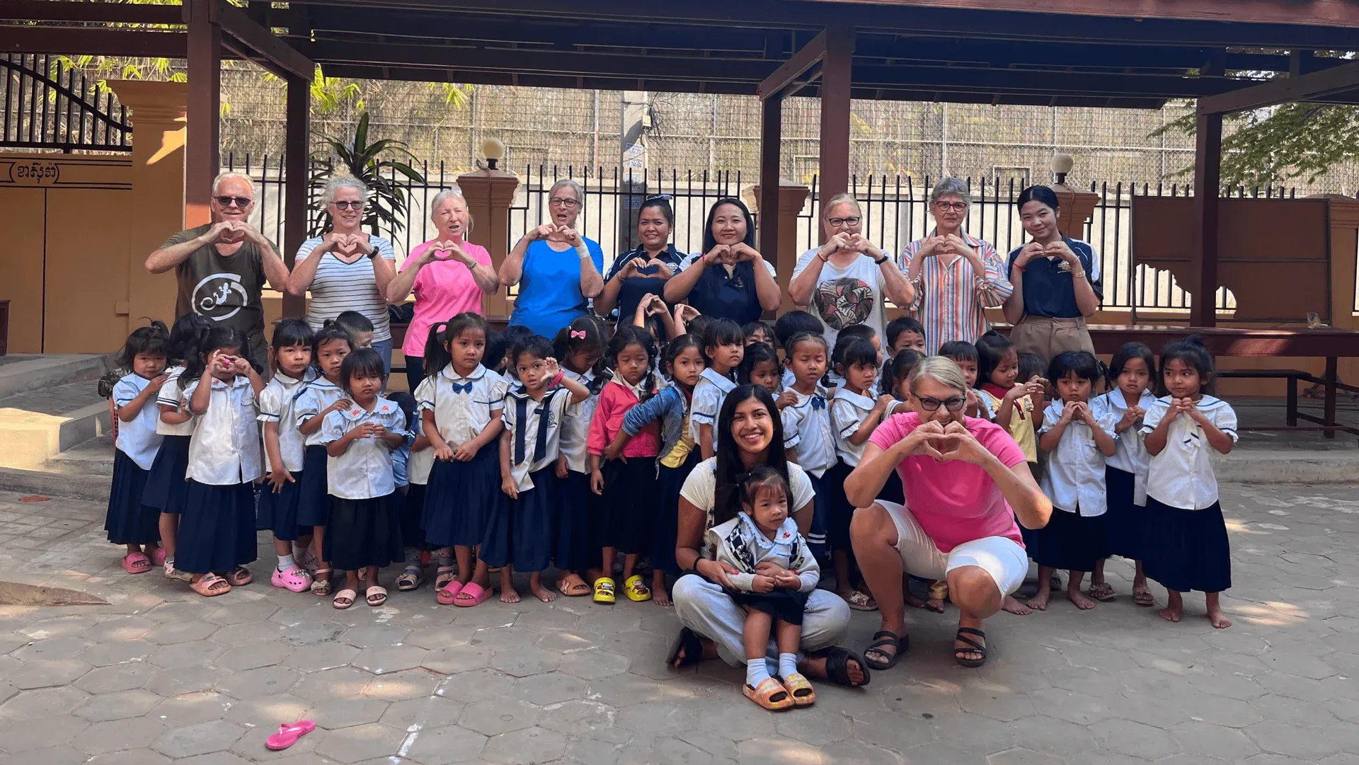 Volunteers and schoolchildren forming heart shapes with their hands